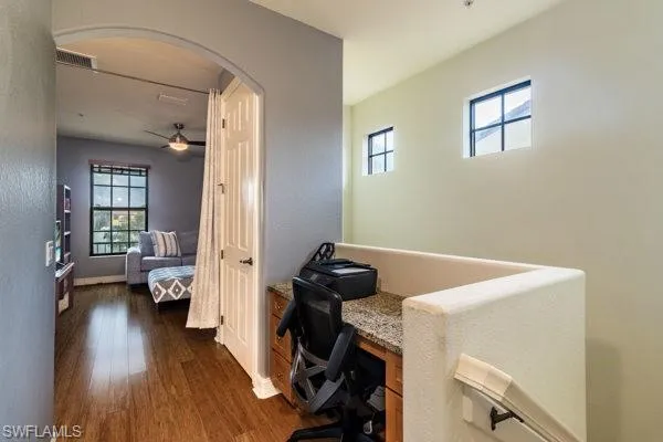Office featuring dark hardwood / wood-style flooring, a wealth of natural light, built in desk, and ceiling fan