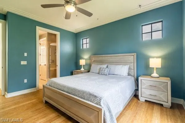 Bedroom with ornamental molding, light wood-type flooring, ceiling fan, and connected bathroom