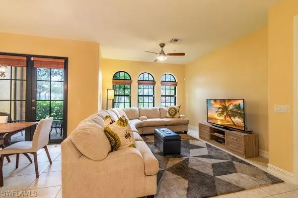 Tiled living room with ceiling fan and plenty of natural light