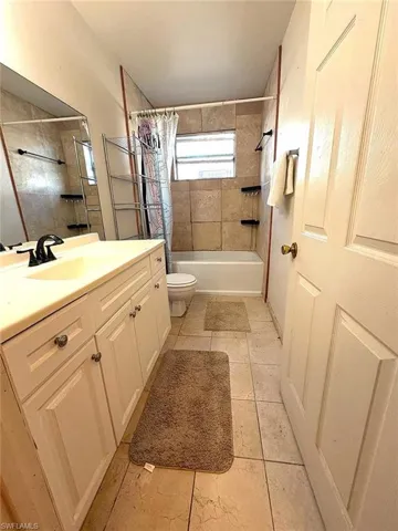 Bathroom featuring vanity, shower / bath combo with shower curtain, and light tile patterned floors