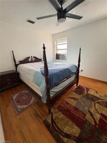 Bedroom featuring wood-type flooring, ceiling fan, and a textured ceiling