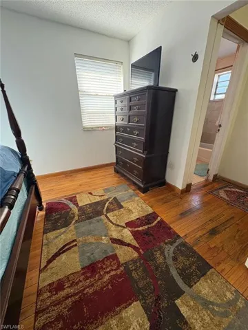 Bedroom with light wood-style floors, a textured ceiling, and connected bathroom