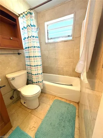 Full bath featuring tile walls and shower / bathtub combination with curtain