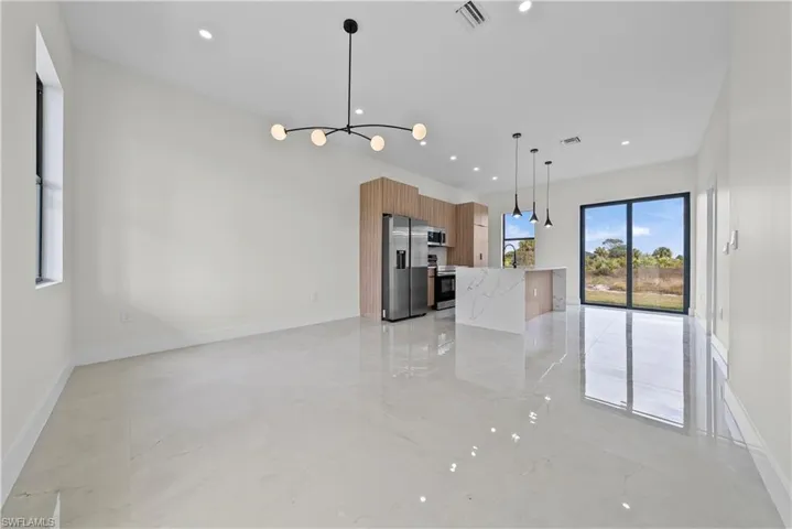 Kitchen featuring modern cabinets, wood finish cabinetry, stainless steel appliances, light stone counters, and open floor plan