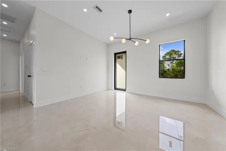 Spare room with a chandelier and baseboards