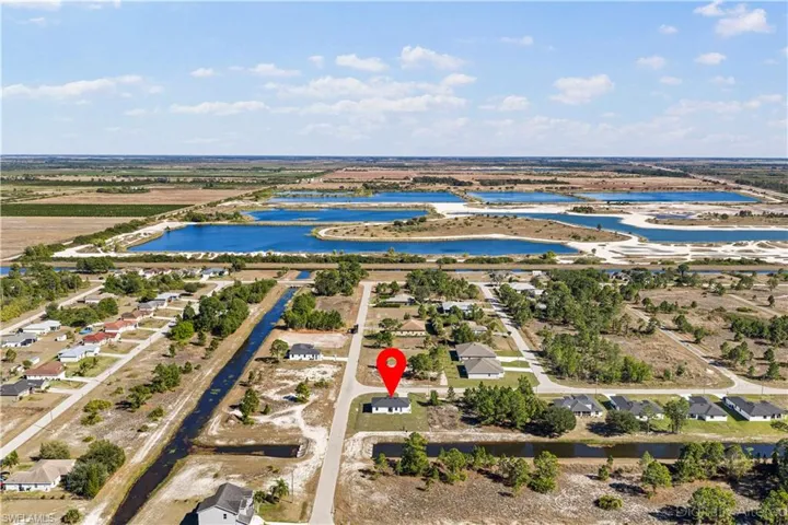 Aerial view of property and surrounding area featuring a nearby body of water and nearby suburban area