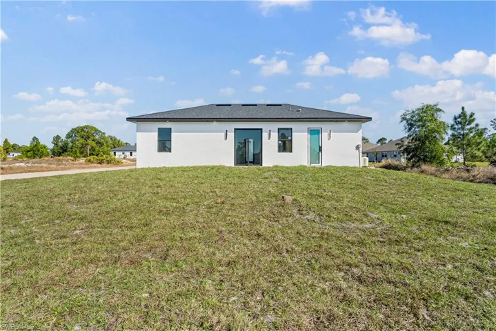 Back of property with a lawn and stucco siding