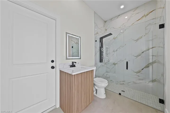 Bathroom featuring a marble finish shower, vanity, and recessed lighting