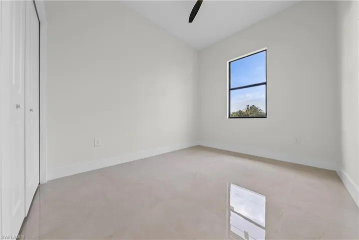 Unfurnished bedroom featuring vaulted ceiling, a closet, and ceiling fan