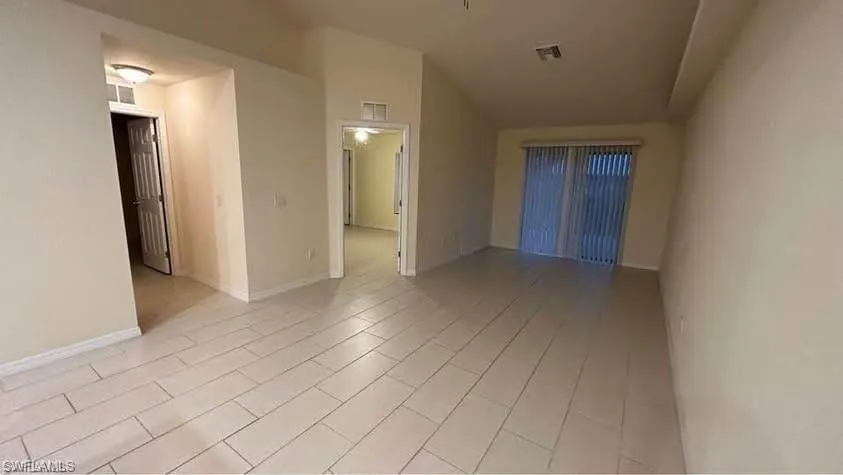 Empty room featuring vaulted ceiling and baseboards
