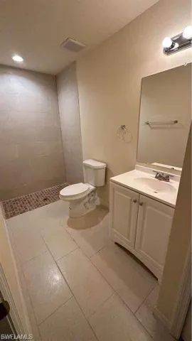 Full bathroom featuring vanity, tiled shower, and light tile patterned floors