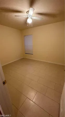 Empty room featuring baseboards and a ceiling fan