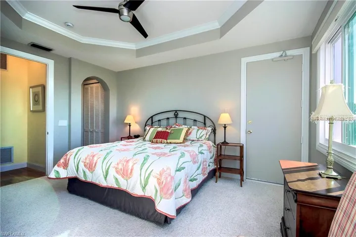 Primary carpeted bedroom featuring recessed ceiling fan, crown molding, and a raised ceiling