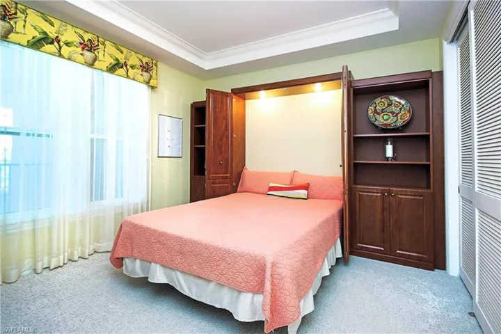 2nd bedroom, Carpet flooring, with a tray ceiling, crown molding, wood cabinetry built-ins and closet