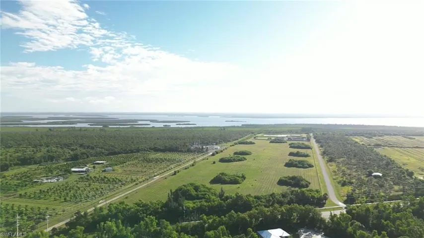Aerial view of sparsely populated area with a nearby body of water and rows of crops
