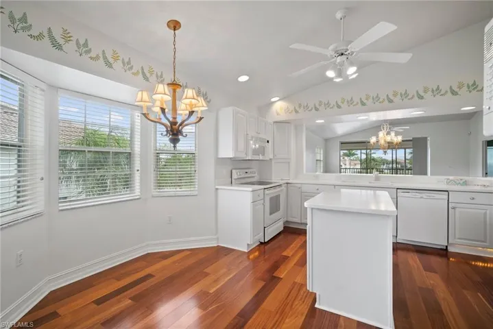Kitchen with white appliances, vaulted ceiling, a wealth of natural light, and kitchen peninsula