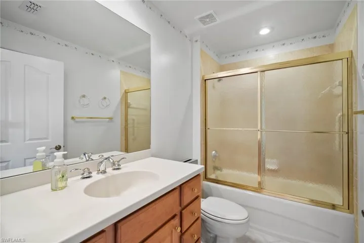 Full bathroom with vanity, toilet, and bath / shower combo with glass door