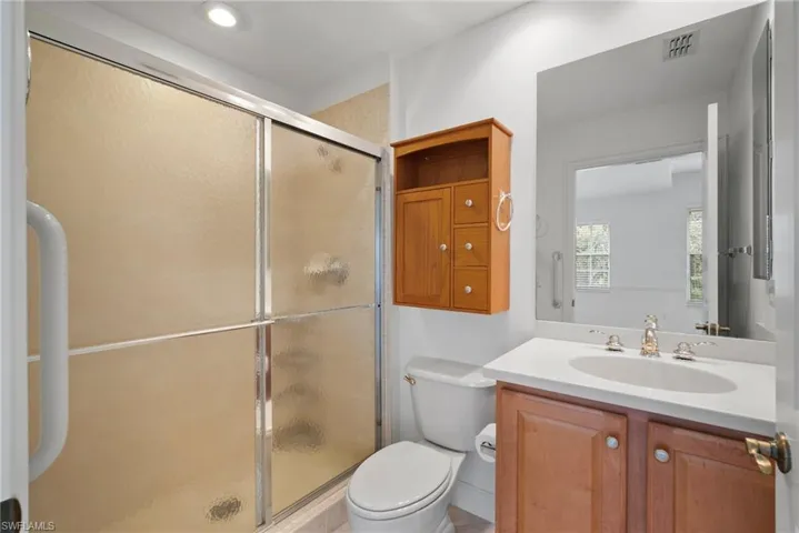 Bathroom featuring vanity, walk in shower, and toilet
