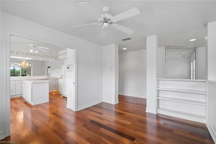 Empty room with hardwood / wood-style flooring and ceiling fan with notable chandelier
