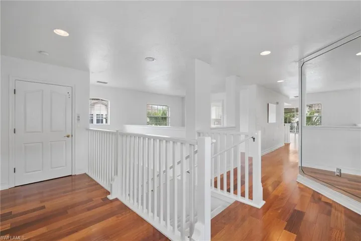 Corridor featuring a textured ceiling, wood-type flooring, and plenty of natural light