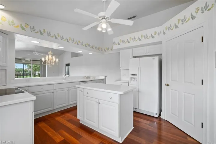 Kitchen with a kitchen island, white cabinetry, white refrigerator with ice dispenser, and dark hardwood / wood-style floors