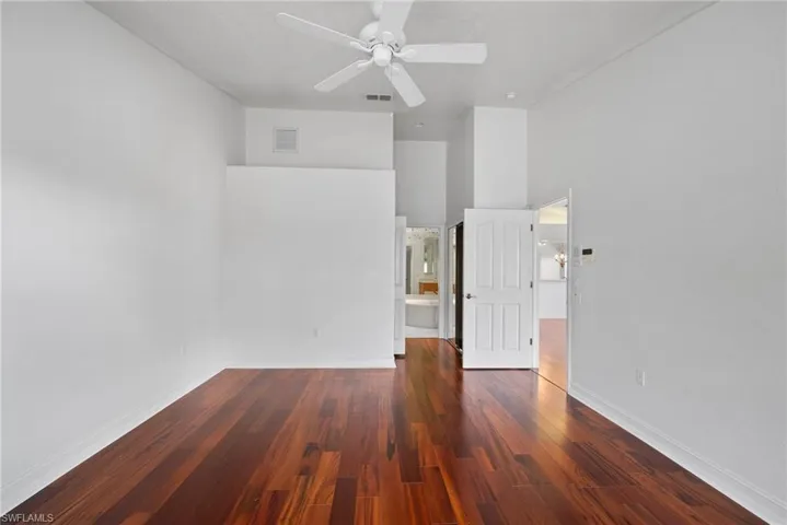Unfurnished room featuring dark wood-type flooring, a high ceiling, and ceiling fan