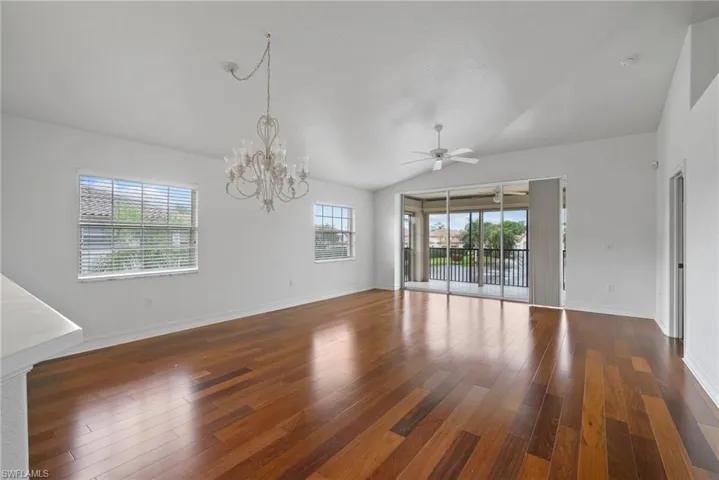 Unfurnished room featuring lofted ceiling, dark hardwood / wood-style floors, and ceiling fan with notable chandelier