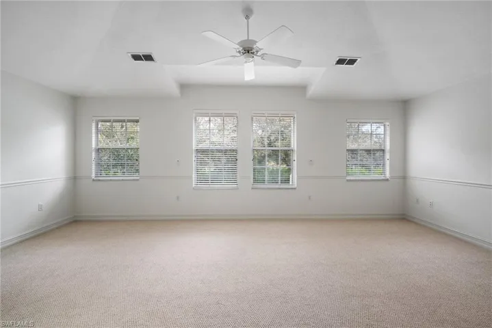 Carpeted spare room featuring ceiling fan and a wealth of natural light