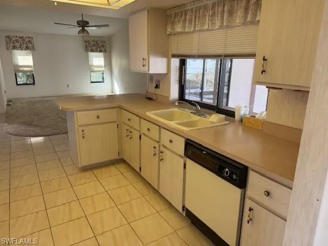 Kitchen featuring white dishwasher, plenty of natural light, kitchen peninsula, and sink