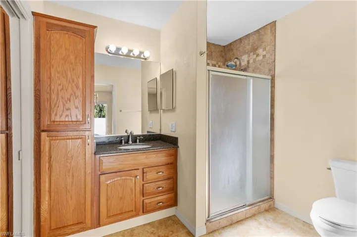 Bathroom with vanity, tile patterned floors, toilet, and an enclosed shower
