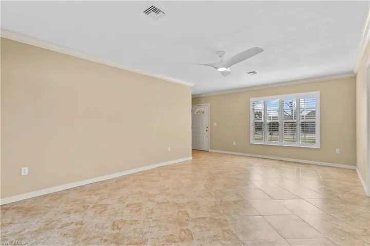 Tiled empty room featuring crown molding and ceiling fan