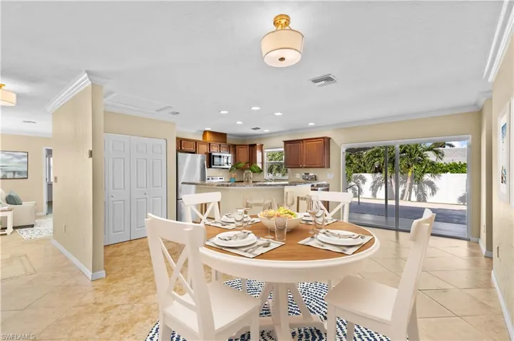 Tiled dining space featuring crown molding and sink