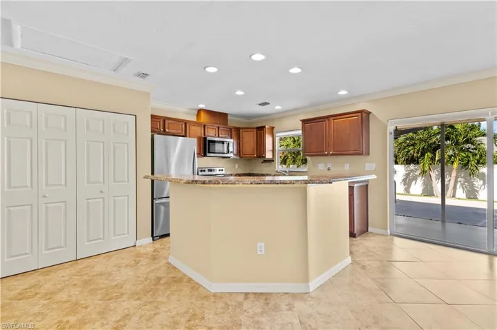 Kitchen with a healthy amount of sunlight, stainless steel appliances, ornamental molding, and a center island