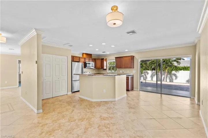 Kitchen featuring a kitchen island, crown molding, stainless steel appliances, and light tile patterned floors