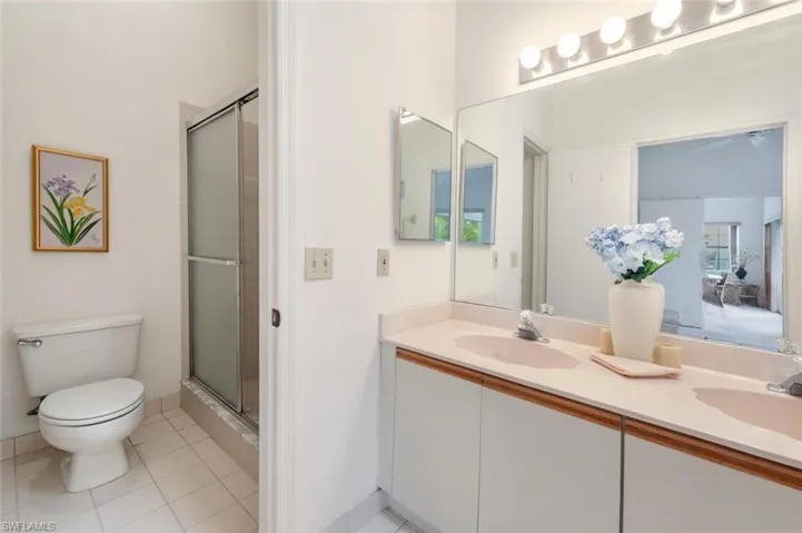 Bathroom with double vanity, light tile patterned flooring, and a shower stall