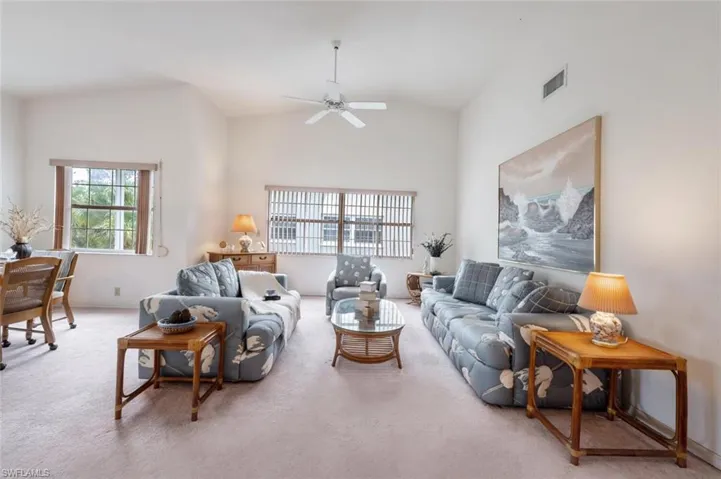 Living area with carpet flooring, a ceiling fan, and high vaulted ceiling