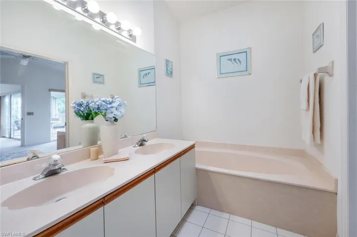 Full bath featuring light tile patterned floors, a bath, and double vanity