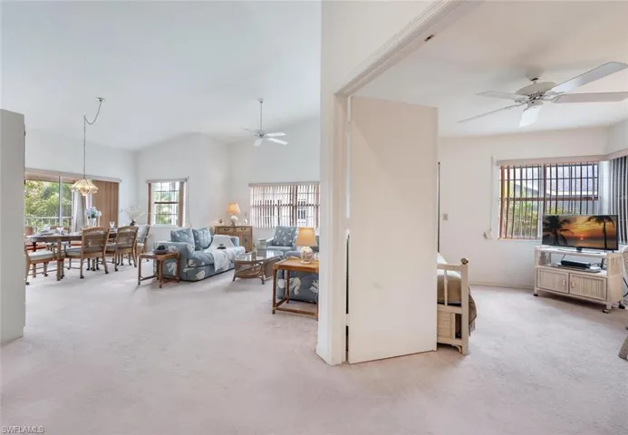 Living area featuring plenty of natural light, ceiling fan, carpet flooring, and vaulted ceiling