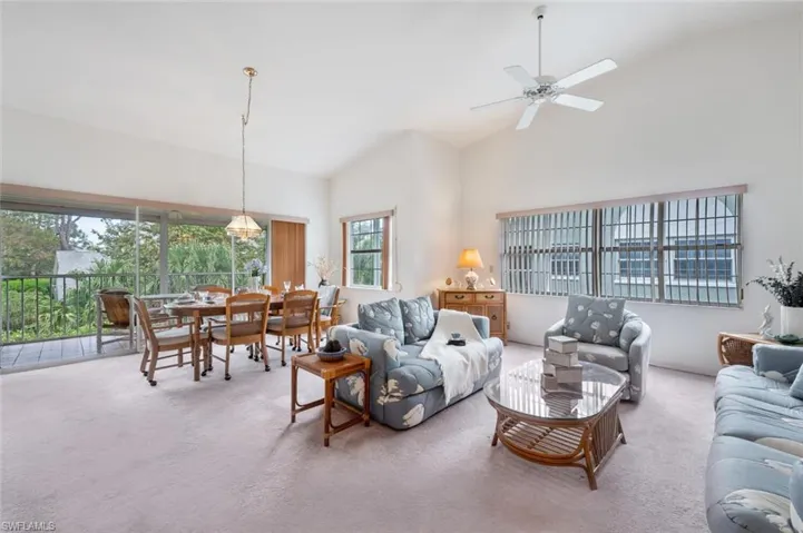 Living area featuring high vaulted ceiling, carpet flooring, and ceiling fan