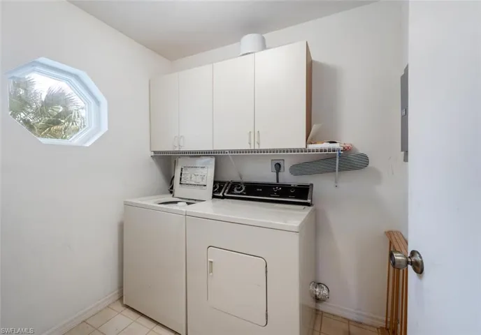Laundry area featuring separate washer and dryer, cabinet space, and light tile patterned flooring