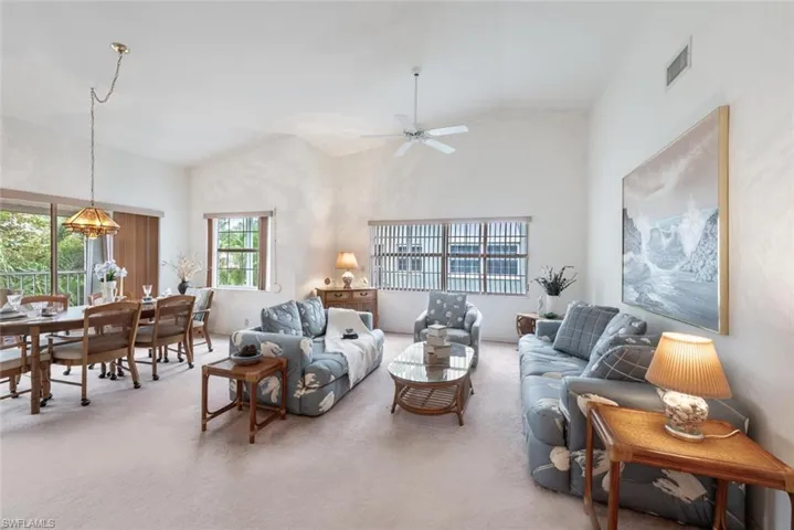 Living area with lofted ceiling, carpet, and ceiling fan