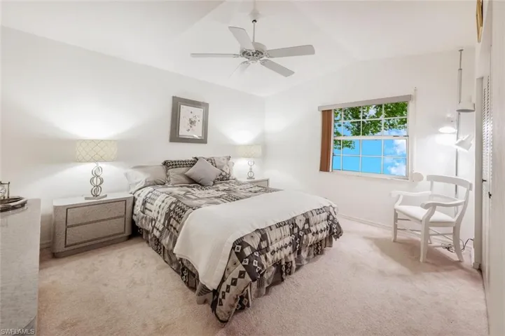 Bedroom with vaulted ceiling, light carpet, and ceiling fan