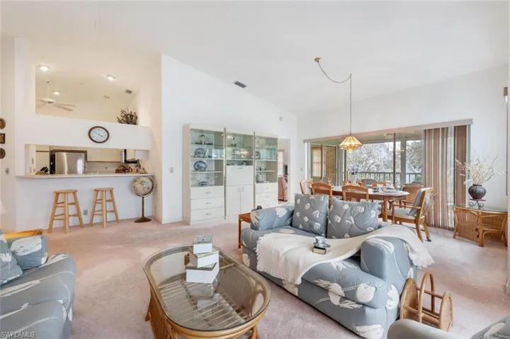 Carpeted living room featuring ceiling fan and lofted ceiling