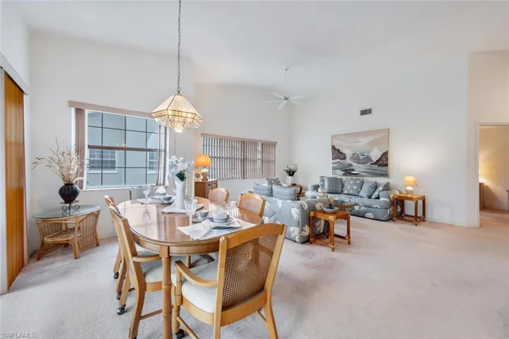 Dining area featuring light colored carpet, ceiling fan, and a towering ceiling