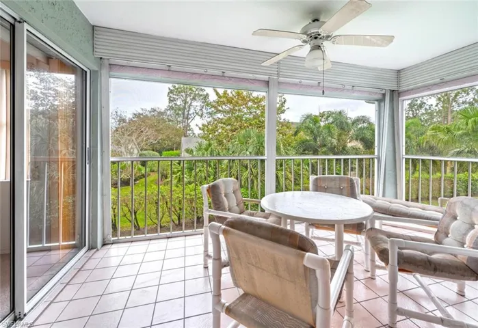 Sunroom / solarium featuring ceiling fan and view of scattered trees
