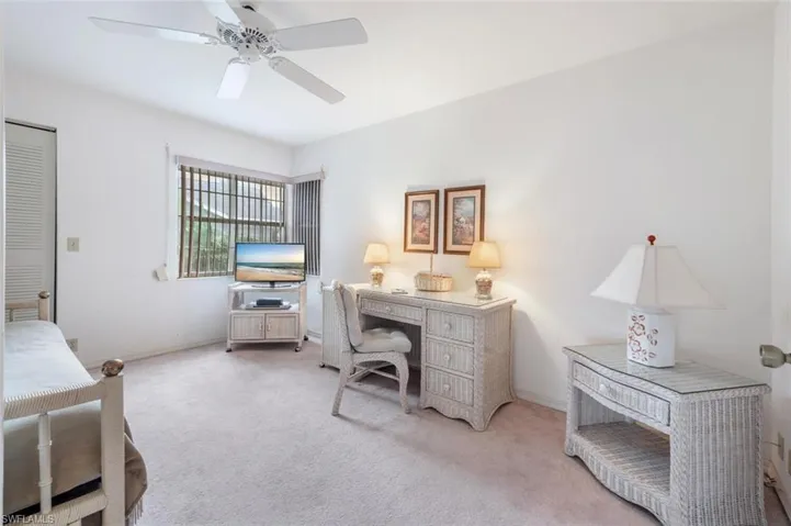 Carpeted office space with a ceiling fan and baseboards