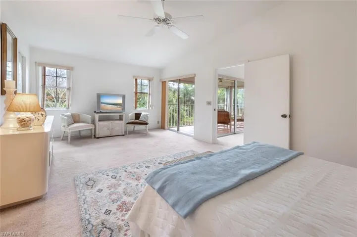 Bedroom featuring access to exterior, light carpet, a ceiling fan, and vaulted ceiling