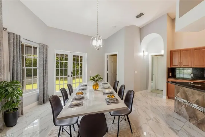Dining area featuring french doors, high vaulted ceiling, and a chandelier