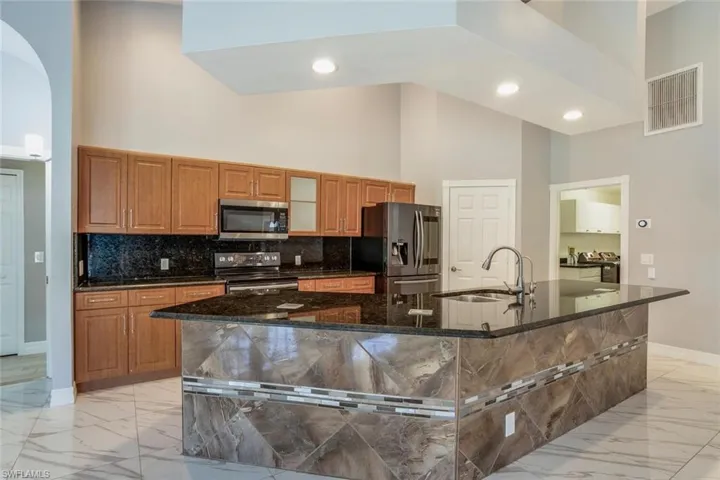 Kitchen featuring a large island, high vaulted ceiling, sink, and appliances with stainless steel finishes