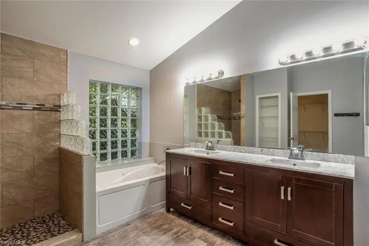 Bathroom featuring vanity, wood-type flooring, lofted ceiling, and shower with separate bathtub